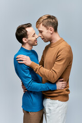 Two men in casual attire embracing in a loving stance.