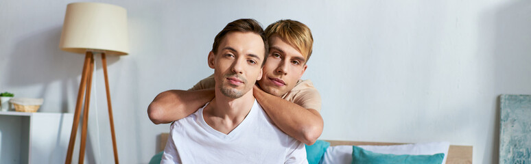 Loving gay couple in casual attire cuddling in a cozy room.