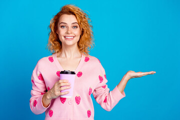 Photo of attractive young woman hold coffee paper cup palm empty space dressed stylish pink clothes isolated on blue color background - obrazy, fototapety, plakaty