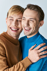 Obraz premium Two smiling men in casual attire hugging each other warmly.