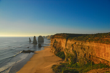 Beautiful coastline view as the setting sun casts a golden hue over limestone cliffs and rock...