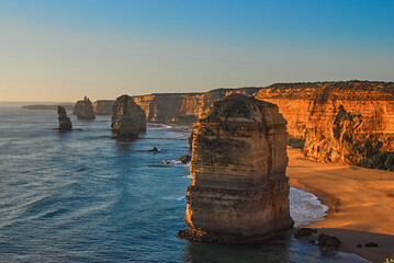 Beautiful view of limestone cliffs and rock formations cast in the golden hue of sunset along the southern coast of Victoria, Australia. - Powered by Adobe
