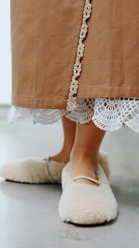 female legs in sheep's wool shoes and folk traditional embroidered long skirt. vertical video