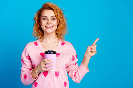 Photo of lovely young lady hold coffee paper cup point empty space dressed stylish pink clothes isolated on blue color background