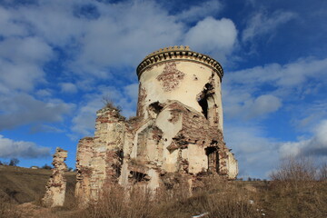 Ruins of an old castle tower against a background of blue sky with white clouds