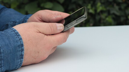 close-up of a man's hands using his smartphone in the garden outdoors