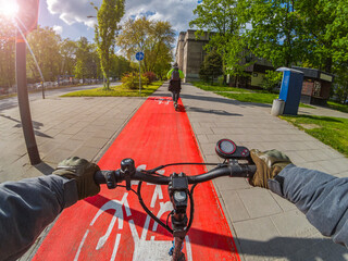 Riding an electric scooter on a bike lane in sunny weather. First-person view.