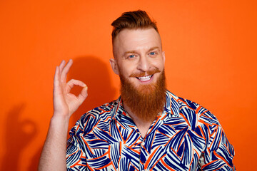 Photo of excited confident guy dressed print shirt showing okey gesture isolated orange color background