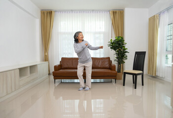 playful asian senior woman dancing in the living room,elderly lifestyle,domestic life,relaxation