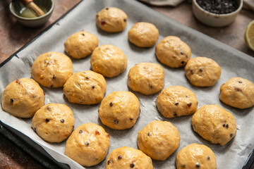 Homemade chocolate and lemon brioche buns rising on baking tray .