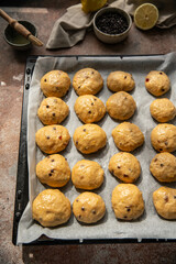 Homemade chocolate and lemon brioche buns rising on baking tray .