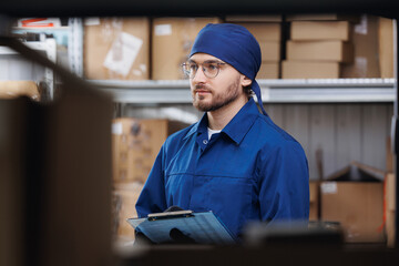 Young worker in blue uniform use clipboard checklist for manage parcel box product in warehouse....