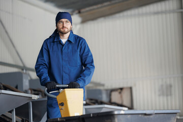 Young man worker with blue uniform with trolley for transporting cedar nuts. Concept modern food...