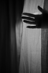 silhouette of a hand behind a curtain.