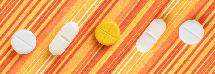 Pills and medicines arranged on an orange striped background. It's a visual representation of...