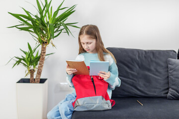 Child Girl Reading Notebook on Couch. Morning preparation before school.