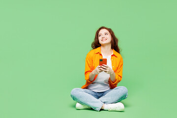 Full body young ginger woman she wear orange shirt white t-shirt casual clothes sits hold in hand...