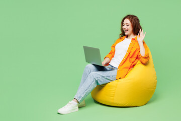 Full body young ginger IT woman wears orange shirt white t-shirt casual clothes sit in bag chair...