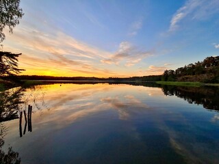 Sunset Reflections: The early evening sky, painted with shades of orange and blue, reflects on the...