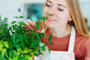  girl in the kitchen sniffs a leaf of parsley and dill