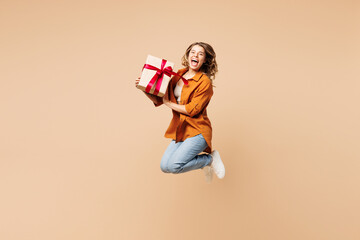 Full body young excited woman she wear orange shirt casual clothes jump high hold present box with...