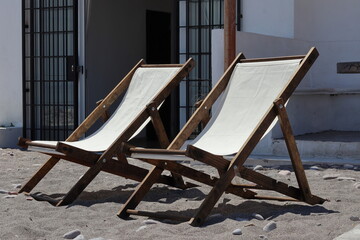Two portable reclining beach chairs, solid wood frame with white polyester canvas, on the beach
