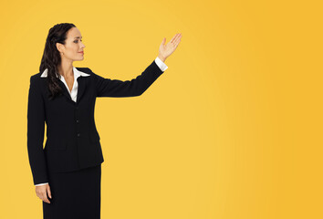 Profile image - smiling woman wear confident suit, showing at mock up slogan text empty blank place. Business ad concept. Isolated against yellow wall background. Wide banner image