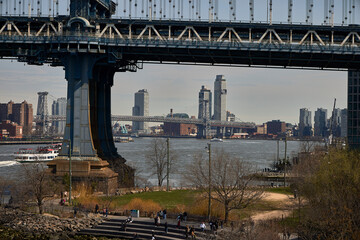 New York (United States), March 22, 2024. Bridge over the Hudson River. It joins the boroughs of Manhattan and Brooklyn. In addition to heavy vehicle traffic, many passenger boats navigate the river. - obrazy, fototapety, plakaty