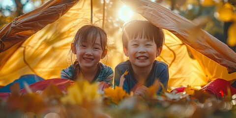 Joyful Young Siblings Playing in a Homemade Tent Surrounded by Autumn Leaves at Sunset, Capturing a Heartwarming Childhood Moment