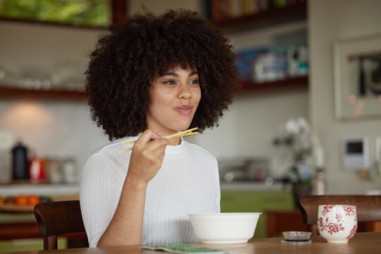 Black woman, chopsticks and food for lunch in kitchen fine dining for healthy diet, experience or hunger. Female person, plate and asian cuisine or ramen in home for snack, nutrition and eating