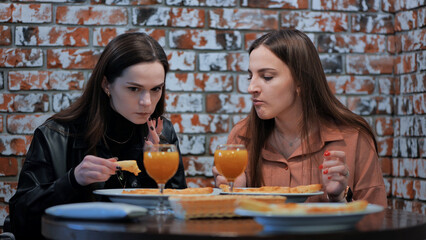 Two cheerful girls in a cafe having dinner.