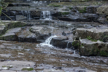 Small waterfalls or cascades falling over dark rock layers and intervening flat rock areas in Giba Gorge, a nature reserve situated on the Giba River in Gillitts in KwaZulu Natal in South Africa.