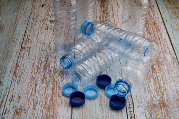 Overhead view of closed and open plastic bottles placed on a wooden table for recycling.