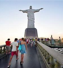People, christ and statue with tourist in rio de Janeiro of redeemer for sightseeing, landmark or view of sculpture. Group, community or crowd on tour, trip or monument of iconic attraction in Brazil