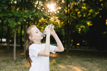 Photo of child girl drinking water after workout outdoors
