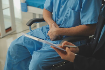 Midsection of female nurse checking blood pressure of woman sitting on wheelchair in clinic