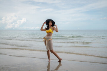 Woman in a bikini relishing her time on a tropical beach. She relaxes on the sandy shore, embodying the essence of summer vacation.