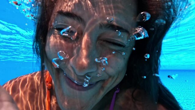 Underwater close-up of playful woman puffing cheeks