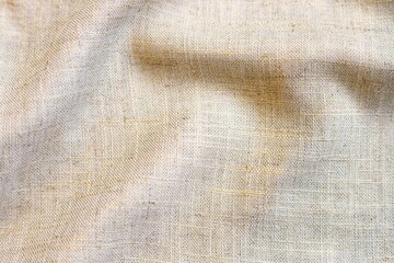 Beige linen fabric texture with folds. Close up.