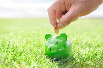 Saving money in green piggy bank, savings, accounting, banking and business account or sustainable...