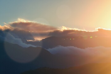Sunset landscape with lens flare, mountains and clouds as an background