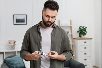 Diabetes test. Man checking blood sugar level with glucometer at home