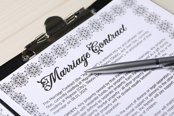 Marriage contract and pen on light wooden table, closeup