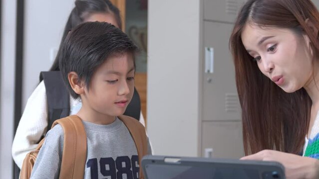 Smiling Asian female lecturer helping children student during classroom. Education knowledge, successful teamwork concept.