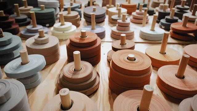 Many colored spools for overlock carpets in a store warehouse. Carpet rolls stacked at store. Move camera