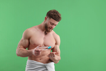 Handsome man with body lotion on green background, space for text