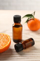 Bottles of tangerine essential oil and fresh fruits on wooden table