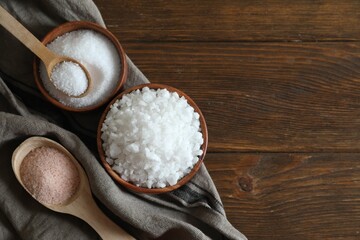 Different types of organic salt on wooden table, flat lay. Space for text