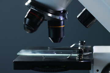 Microscope with glass slide on dark background, closeup