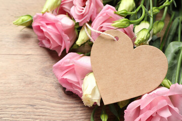 Happy Mother's Day. Beautiful flowers and blank heart shaped card on wooden table, closeup. Space for text